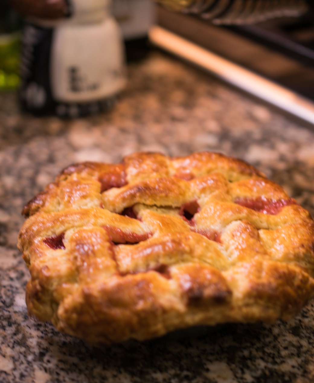 Photo of a small strawberry rhubarb pie topped with a lattice crust